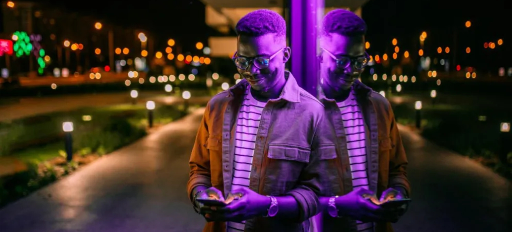 Young man using his phone leaning against a building 1000.jpeg.jpg